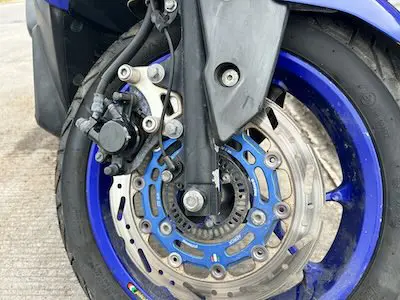 A blue-rimmed motorbike rental wheel and tire in used, but good shape.