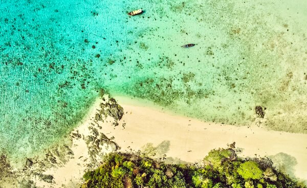 Top-down aerial view of Ko Mai Phai Island (Bamboo Island) showing the abundant sand, rocky shore, and crystal clear turquoise waters.