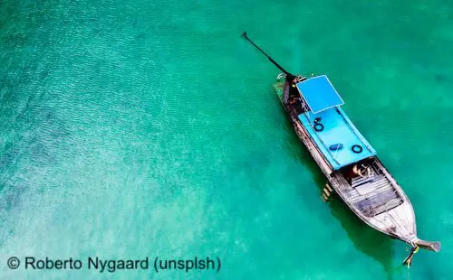 Longtail boat seen in the Krabi ocean in aerial view.